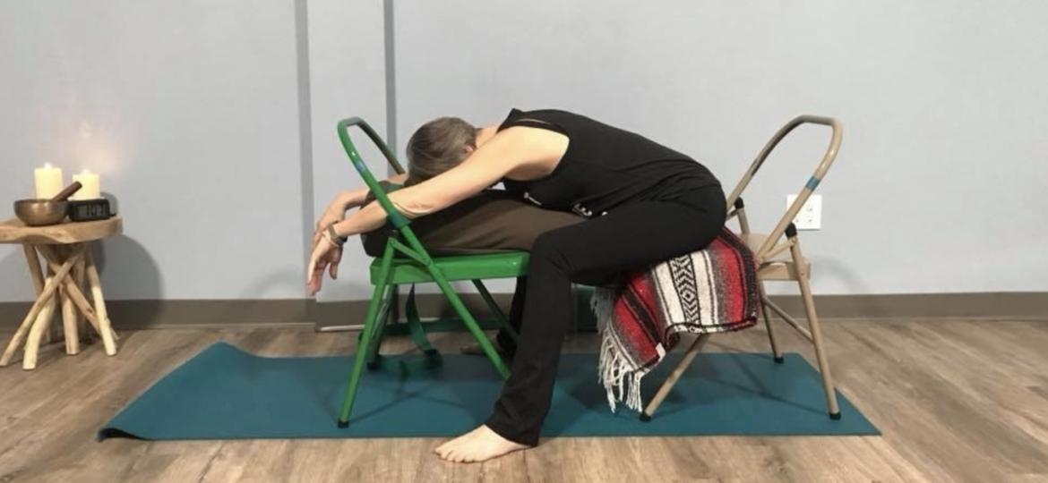 Moya McGinn Mathews demonstrates supported child's pose with two chairs and a bolster.