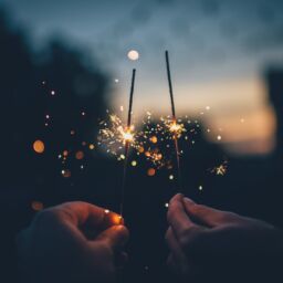 Two hands hold burning sparklers in the dark on New Year's Eve.