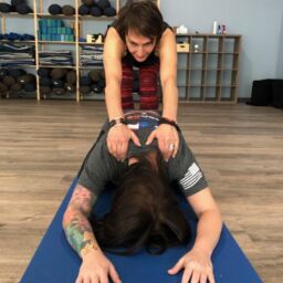 Holly Schramm provides a hands-on assist in Savasanassage child's pose.