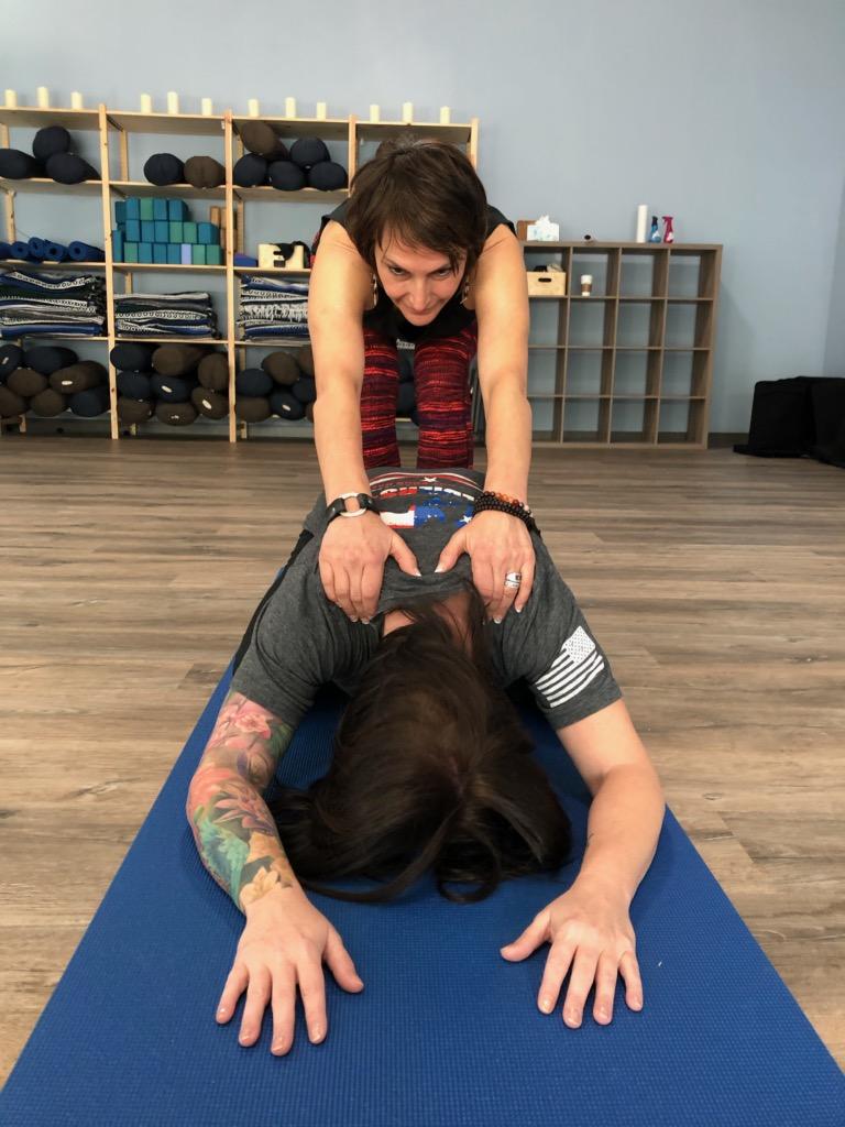 Holly Schramm provides a hands-on assist in Savasanassage child's pose.